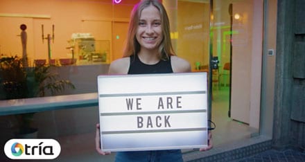 Woman Holding a We Are Back Sign